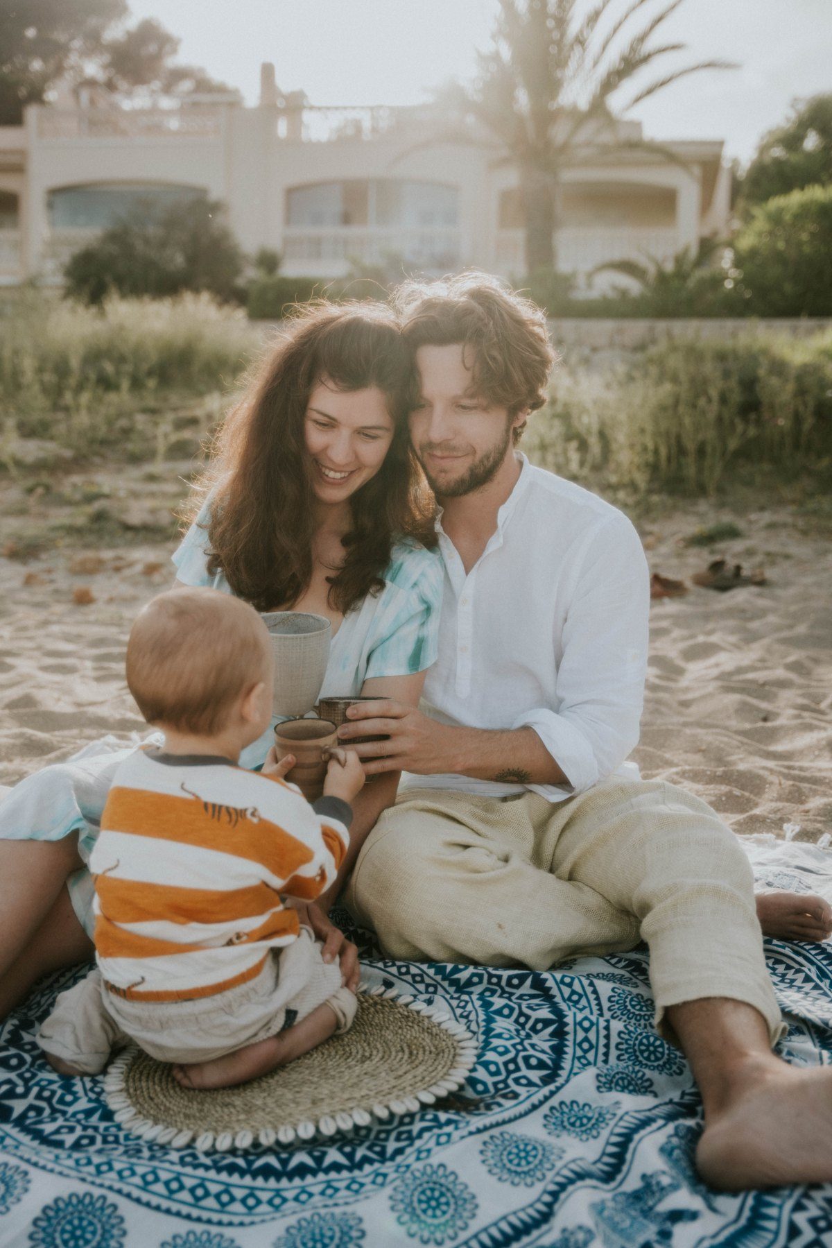 Alex mit seiner Partnerin und seinem Kind auf einer Decke am Strand